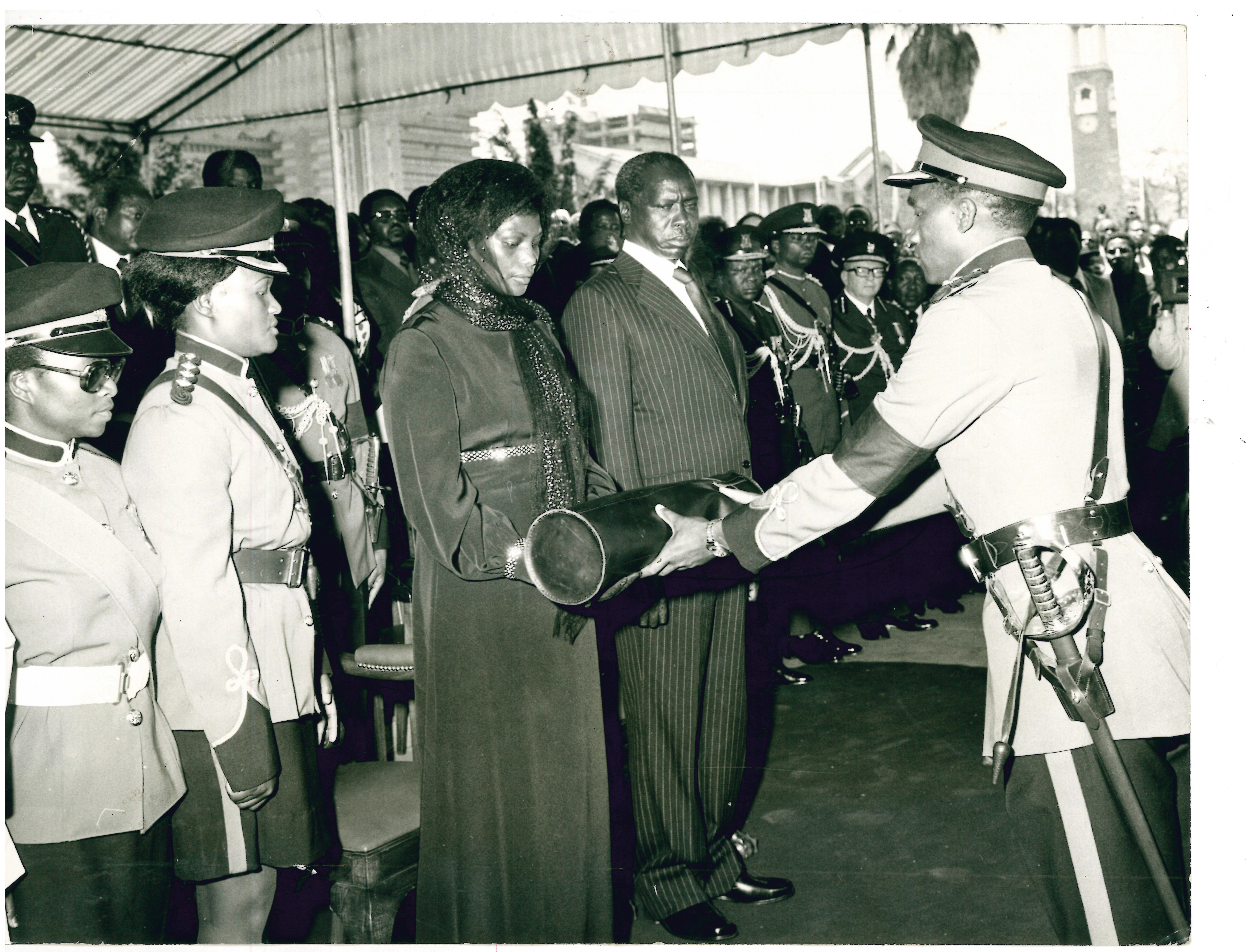 Death of Kenyatta (1978)_Kenya army officer presents Mzee Jomo Kenyatta presidential standard and the national flag to Mama Ngina Kenyatta while President Moi looks on during funeral mass_31.8.1978