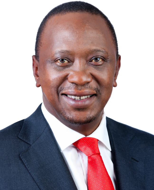 Colour portrait of smiling middle-aged President Uhuru Kenyatta in a dark suit, white shirt and bright red tie against a light gray background.