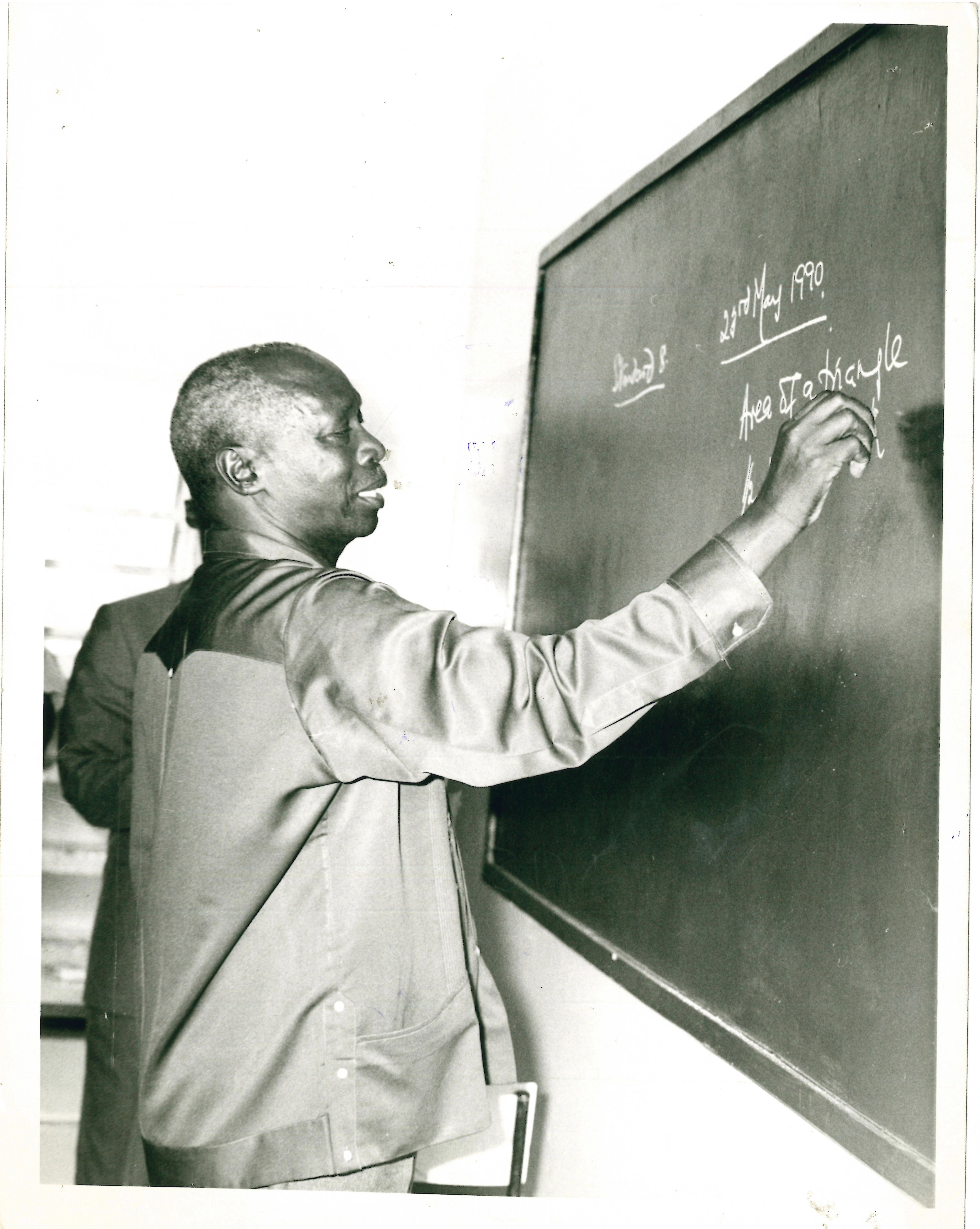 President Daniel Arap Moi a former teacher practices his skills on a black board during a school visit in Nakuru