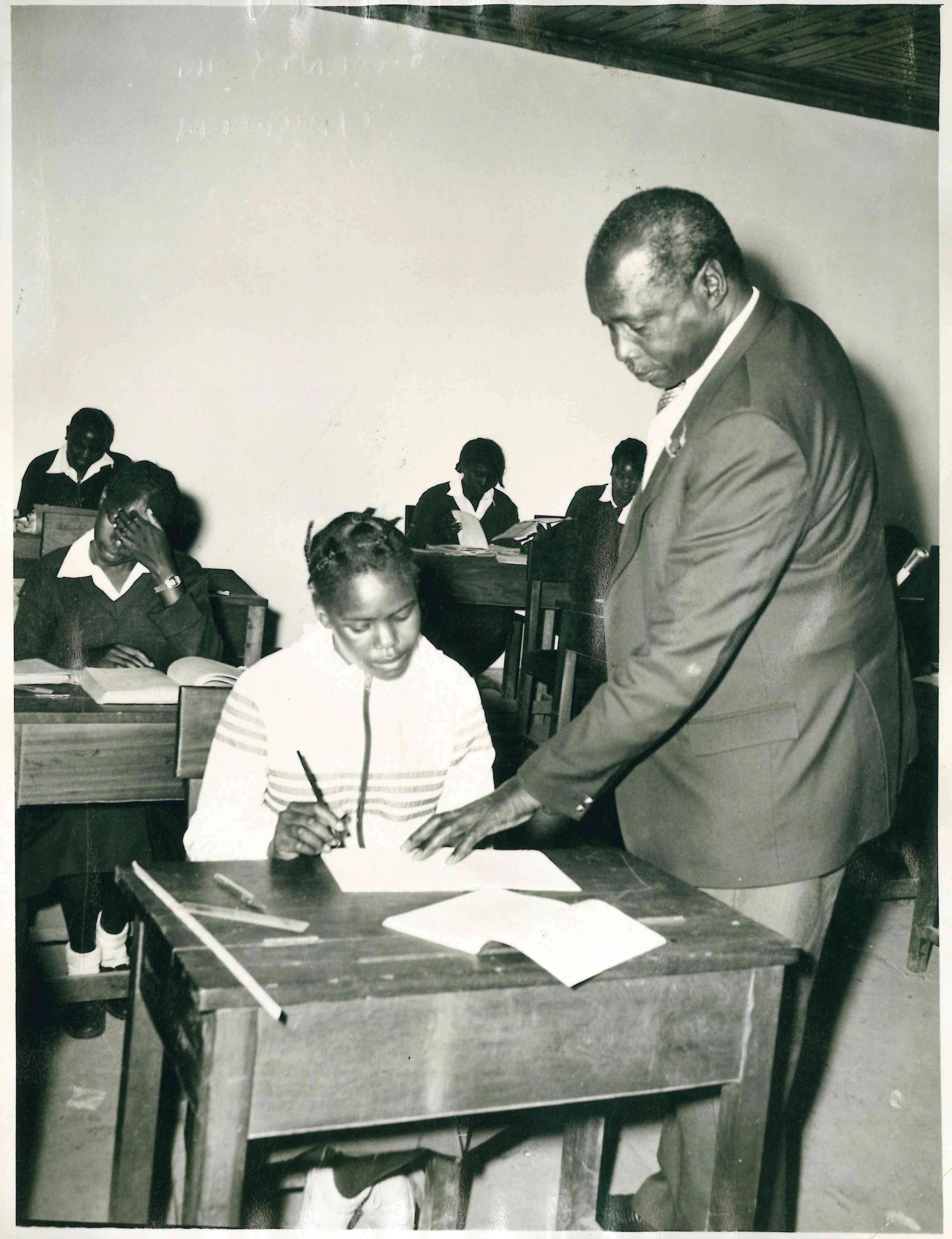 President Daniel Arap Moi checks the book of a student while in classroom during a School tour in Nairobi